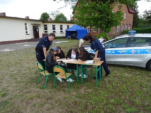 młodzież rozwiązuje krzyżówki. Obok stoją policjanci