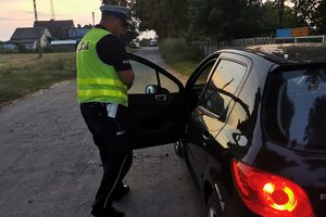 policjant kontroluje auto osobowe