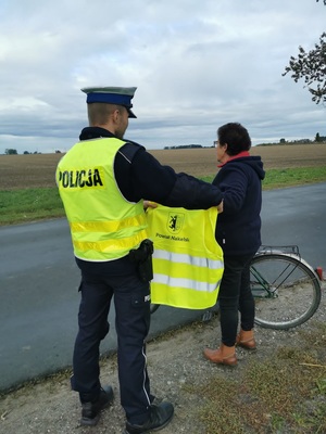 policjant przekazuje kamizelkę rowerzystce