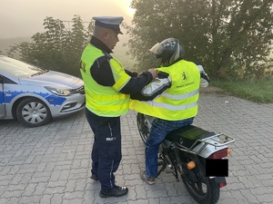 cyklista ubiera kamizelkę otrzymaną od policjanta