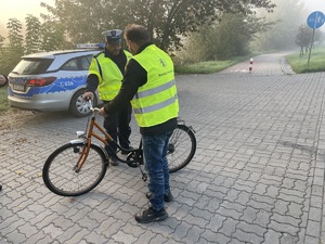 rowerzysta w kamizelce obok stoi policjant