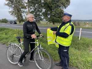 policjant przekazuje kamizelkę rowerzyście