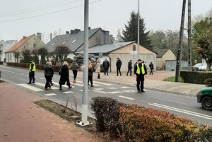 piesi przechodzą przez jezdnię pod nadzorem policjantów