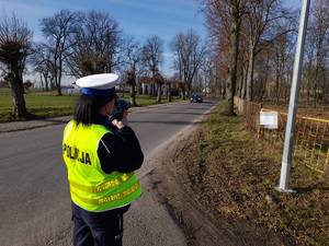 policjantka kontroluje prędkość pojazdu urządzeniem