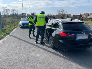 policjanci kontrolują pojazd osobowy koloru ciemnego