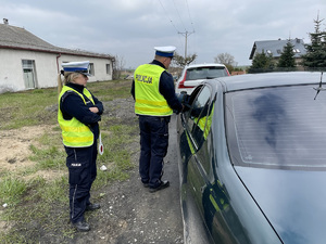 policjanci kontrolują auto osobowe koloru ciemnego