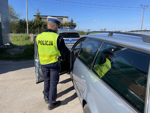 policjant kontroluje auto osobowe
