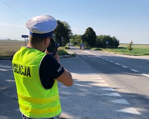 policjant mierzy prędkość nadjeżdżającego auta urządzeniem