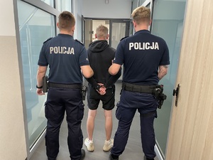 policjanci prowadzą osobę zatrzymaną