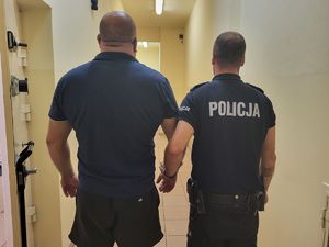 policjant stoi z zatrzymanym mężczyzną