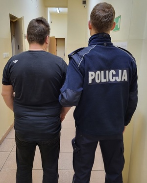 policjant stoi z zatrzymanym mężczyzną