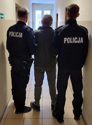 policjant stoi z zatrzymanym