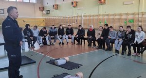 policjant uczy jak udzielać pierwszej pomocy