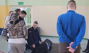 policjant uczy jak udzielać pierwszej pomocy