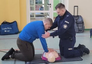 policjant uczy jak udzielać pierwszej pomocy