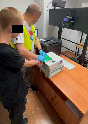policjant skanuje zatrzymanemu linie papilarne z palca